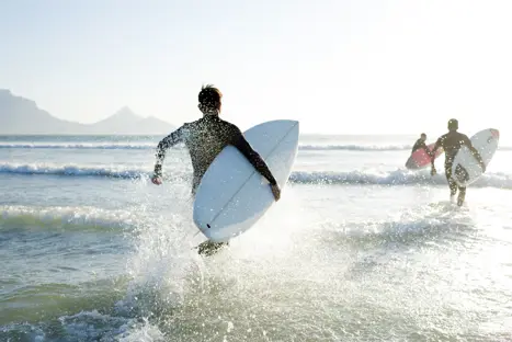 Boys Wearing Their Wetsuits Carrying Their Surfboards Run Into The Sea Gettyimages 525212990
